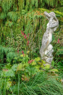 Baharda bir bahçenin cazibesi çiçek açar. Dekorasyondaki kadın heykeli.