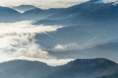 Kışın sis denizinin üzerindeki sisin içindeki dağların silueti. Güney Vosges. Fransa.
