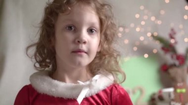 Bulanık kıvırcık kız Noel gözlüğü takıyor, kameraya bakıyor ve gülümsüyor. Noel tatili çocukluk konsepti. Noel 'in tadını çıkarıyorum.
