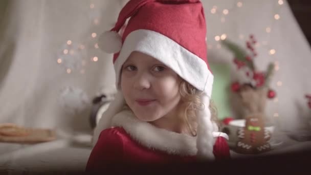 サンタの帽子の少女はクリスマスの時間を楽しんでいます クリスマスプレゼント 子供の頃のコンセプト — ストック動画