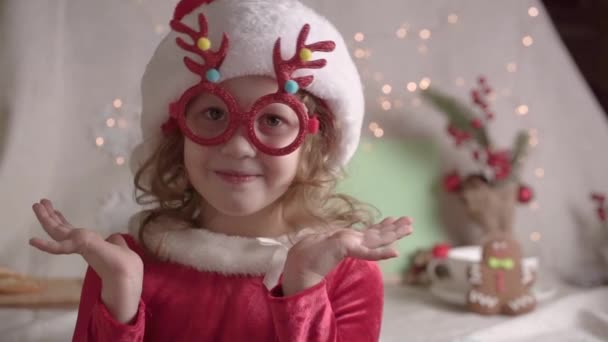 头戴圣诞礼帽 头戴圣诞眼镜 面带微笑的小女孩迷糊了 圣诞节展示了童年的概念 享受圣诞佳节 — 图库视频影像