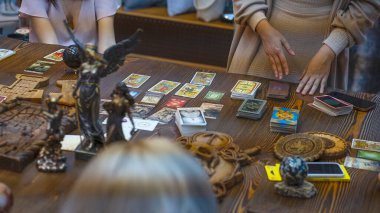 Tarot kartı okuyucusu kartları bir kart dağıtımında düzenler. Masada geleneksel tarot kartlarında fal baktırmak. Seçici odak, Moskova, Rusya-Haziran 2021.
