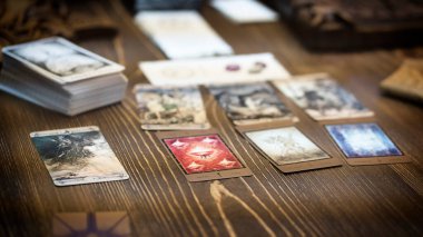 Tarot kartı okuyucusu kartları bir kart dağıtımında düzenler. Masada geleneksel tarot kartlarında fal baktırmak. Seçici odak, Moskova, Rusya-Haziran 2021.