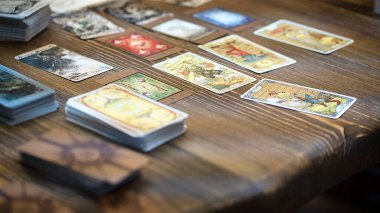 Tarot kartı okuyucusu kartları bir kart dağıtımında düzenler. Masada geleneksel tarot kartlarında fal baktırmak. Seçici odak, Moskova, Rusya-Haziran 2021.