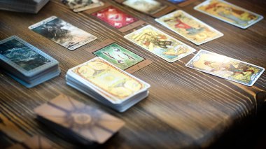 Tarot kartı okuyucusu kartları bir kart dağıtımında düzenler. Masada geleneksel tarot kartlarında fal baktırmak. Seçici odak, Moskova, Rusya-Haziran 2021.
