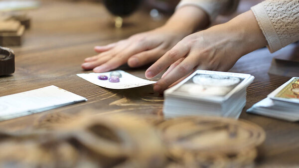 Tarot card reader arranges cards in a card spread. Fortune-telling on traditional tarot cards on the table. Selective focus, Moscow, Russia-June 2021.