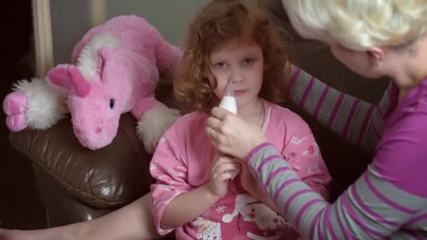 Rozmazaný pohled na matku s použitím nosní aspirátor lékařské. Dcera má nudle. — Stock video