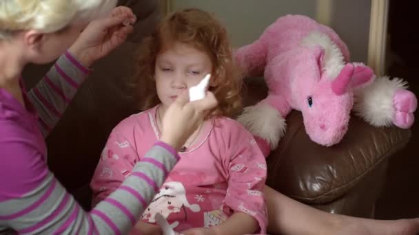 Vue floue d'une mère utilisant un aspirateur nasal médical. Fille a morve. — Video