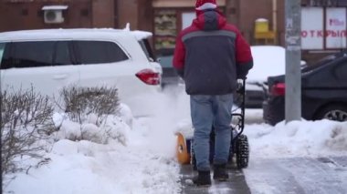 Kışın kar küreme aracının bulanıklığı kar fırtınasının arka planında beyaz karı kaldırıyor. Soğuk mevsim ortamında şehir caddesinde kar temizleme sürecinin yakın görüntüsü