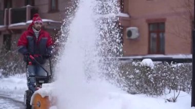 Kışın kar küreme aracının bulanıklığı kar fırtınasının arka planında beyaz karı kaldırıyor. Soğuk mevsim ortamında şehir caddesinde kar temizleme sürecinin yakın görüntüsü