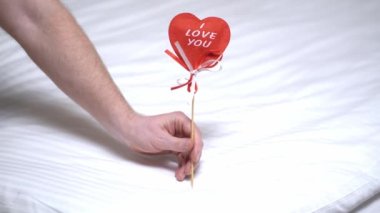 Erkek eli, kadına kalp verir. Kırmızıkalp, seni kadın ve erkeğin ellerinde seviyorum. Sevgililer Günü tebrik kartı. Şenlik arka planı. Tatil çerçevesi.