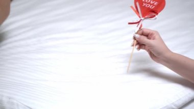 Bir kadının eli, bir erkeğin eline kalp verir. Kırmızıkalp, seni kadın ve erkeğin ellerinde seviyorum. Sevgililer Günü tebrik kartı. Şenlik arka planı. Tatil çerçevesi.