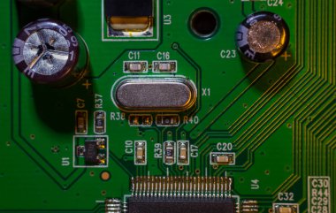 Bilgisayarı (CPU) kontrol etmek için bir kuvars rezonatörünün yakın çekim makro görüntüsü, bir video kartının kontrol panelinin (PCB) bir parçası olan elektronik yazdırılmış devre kartının kuvars saati.
