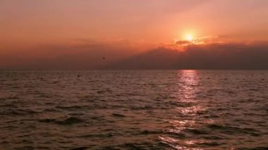 Gün batımında deniz ve ışık dalgaları. Batan güneş suya yansıyor..