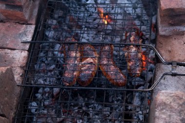 Izgarada mangal dışarıda pişiyor. Açık ateşte ızgara et. Biftek ve domuz sosisi..