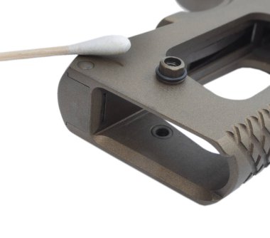 Tabanca kabzası beyaza izole edilmiş pamuklu bezle temizleniyor.