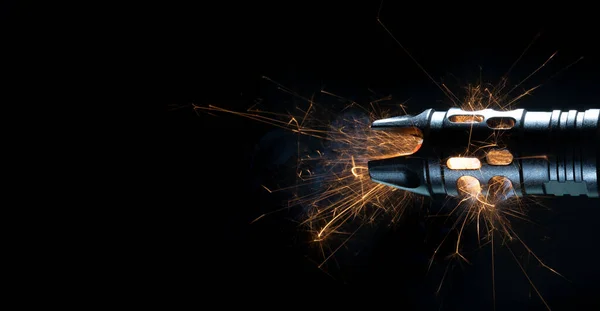 Sparks flying from the barrel of an AR-15 on a black background.