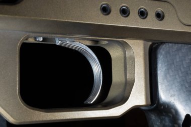 Altın metalik kaplamalı bir tüfeğin desenli tetiğiyle.