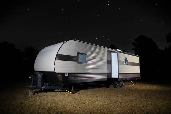 Camping trailer on a grassy spot with bright stars above