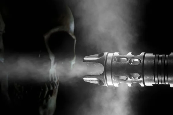 Skull behind a smoking gun barrel on a black background