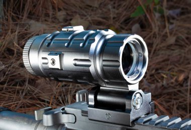 Sight magnifier mounted on an AR-15 rifle outdoors