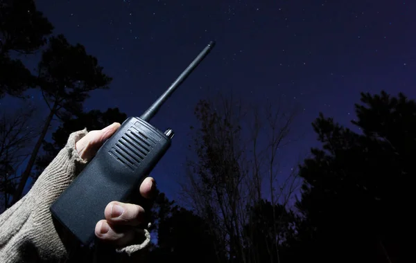 Walkie talkie signaling for help on a starry night in a dark forest
