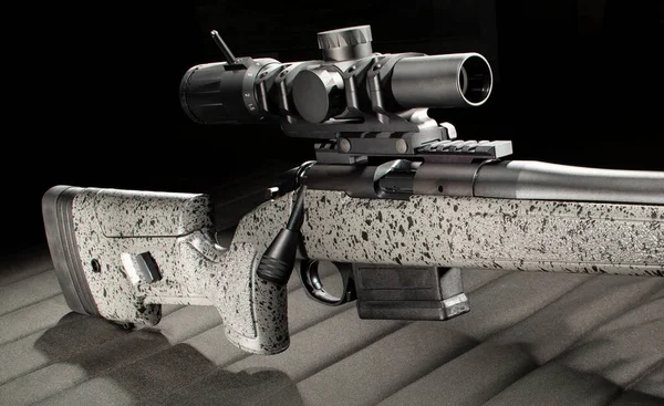 Bolt action rifle loaded with magazine and riflescope on a shooting mat