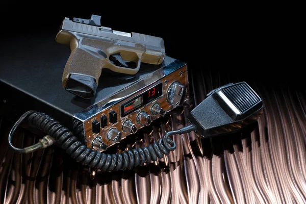 Two way radio and handgun on a copper colored table