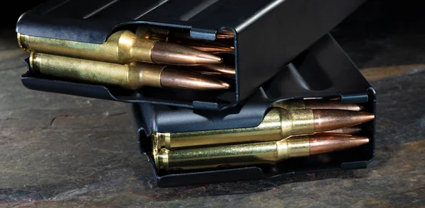 Rifle cartridges loaded in metal magazines on a dark rock