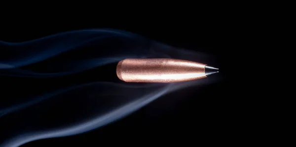 黒い背景に煙が後ろに続く空飛ぶ銅弾 — ストック写真