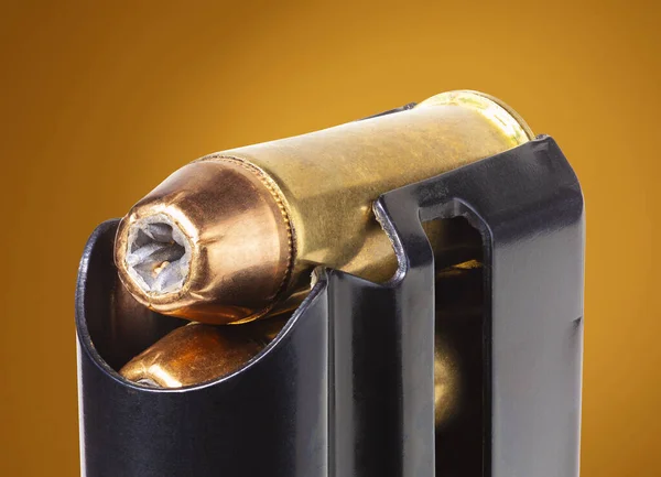 Semi-auto pistol magazine with hollow point bullets on an orange background