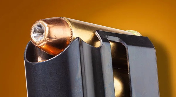 Macro of a gun magazine filled with hollow points on orange with drop shadow
