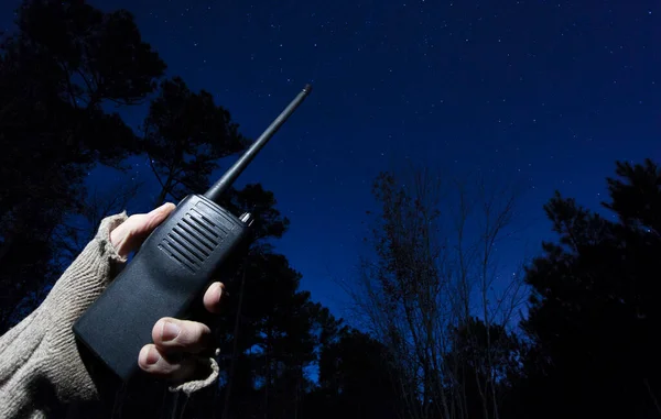 Walkie talkie signaling for help in a starry night in a thick forest