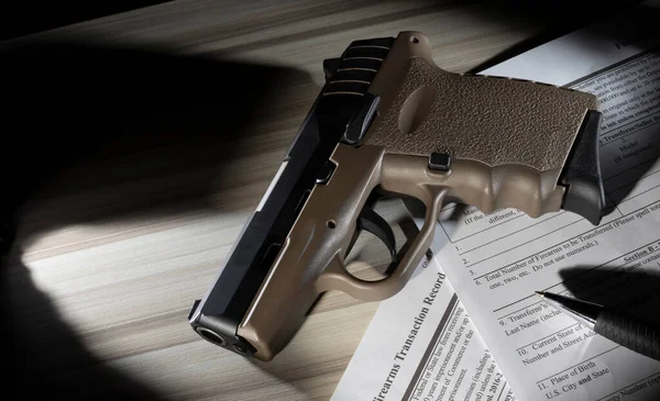 联邦调查局在Nics背景调查中使用的公共域名表格 适用于顶部有米色聚合物手枪和钢笔的火器购买者 — 图库照片