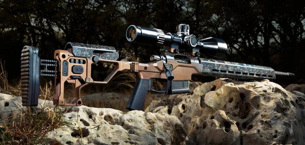Precision rifle with rifle scope outdoors on rocks at dusk