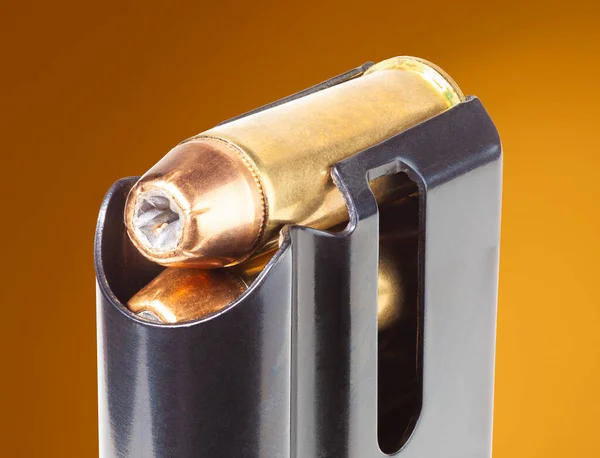 Gun magazine filled with hollow point bullets with brown background