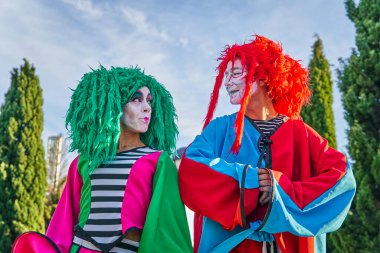 Parkta birbirine bakan renkli kostümlü mutlu palyaçolar.