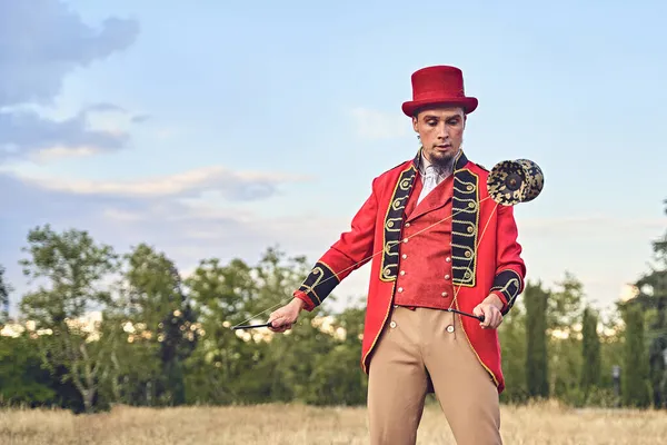 Pandangan depan dari seorang pria berjanggut eksentrik dalam setelan merah dan topi menyulap diabolo. — Stok Foto