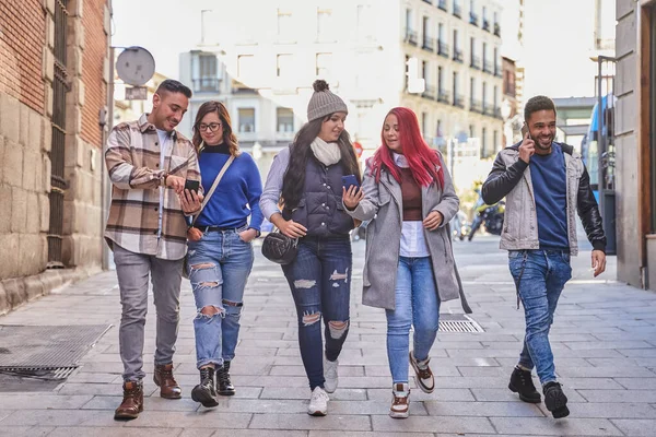 Diversos amigos con teléfonos inteligentes caminando por la calle — Foto de Stock