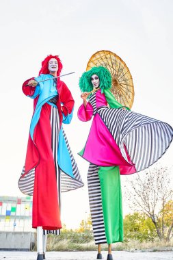 Şemsiyeli ve kılıçlı yaratıcı yürüyüşçüler parkta gösteri yapıyor.