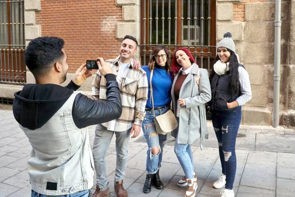 街の通りで友人の彼のグループの彼のスマートフォンで写真を撮るラティーノ男。友情の概念 — ストック写真