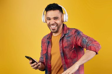 Neşeli İspanyol adam kulaklıkla müzik dinliyor.