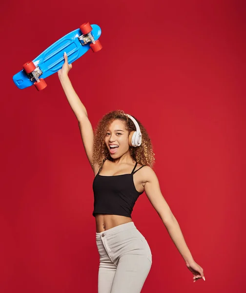 Pozitivní černošky žena s skateboard ve studiu — Stock fotografie