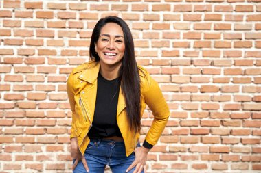 Gülümseyen şık etnik kadın sokakta kameraya bakıyor.