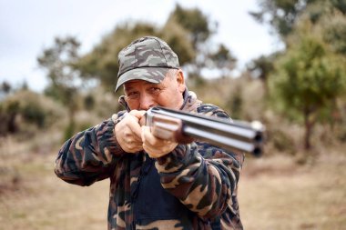 Yaşlı avcı kırsal bölgelere silah doğrultuyor