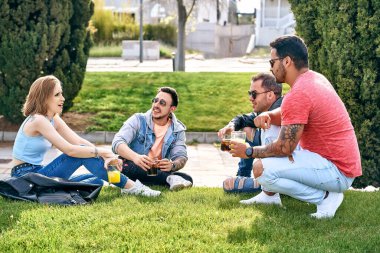 Bir grup arkadaş serinletici içecekler içip yazın parkta takılıyorlar..