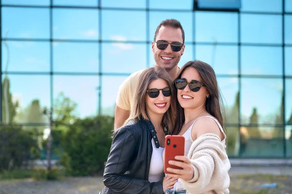 Group of teenage friends with sunglasses happily laughing and taking a selfie on the street. — Foto de Stock