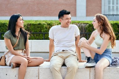 Arkadaşlar dışarıda otururken gülerek ve konuşarak rahatlar. Arkadaşlık ve kentsel yaşam tarzı kavramı.