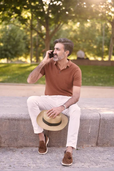 Pria Santai Dengan Topi Tangan Tersenyum Sambil Berbicara Telepon Duduk — Stok Foto
