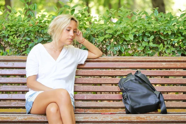 公園のベンチに座っている間に外を見ている若い女性 — ストック写真